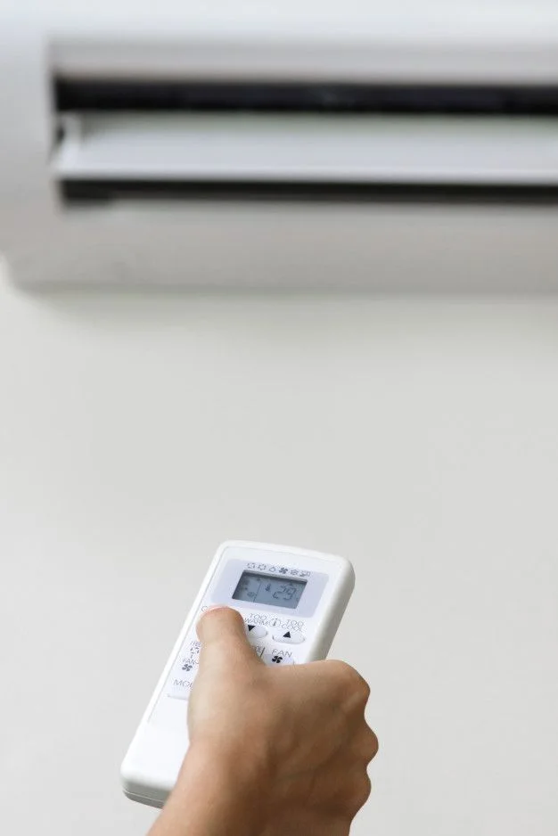Persona usando el control remoto de un aire acondicionado en casa