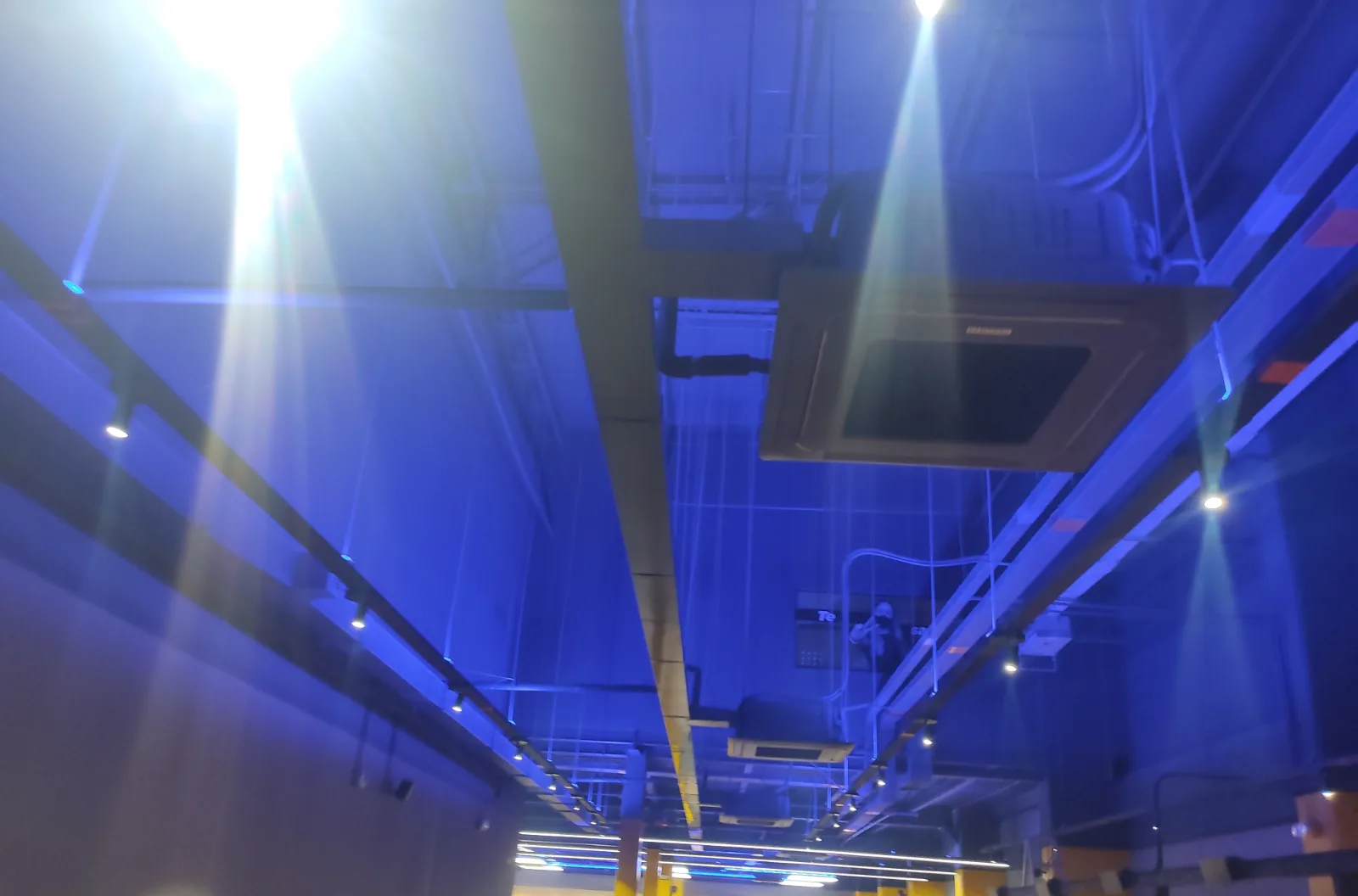 Techo de un gimnasio con luz azul y cassettes de aire acondicionado instalados