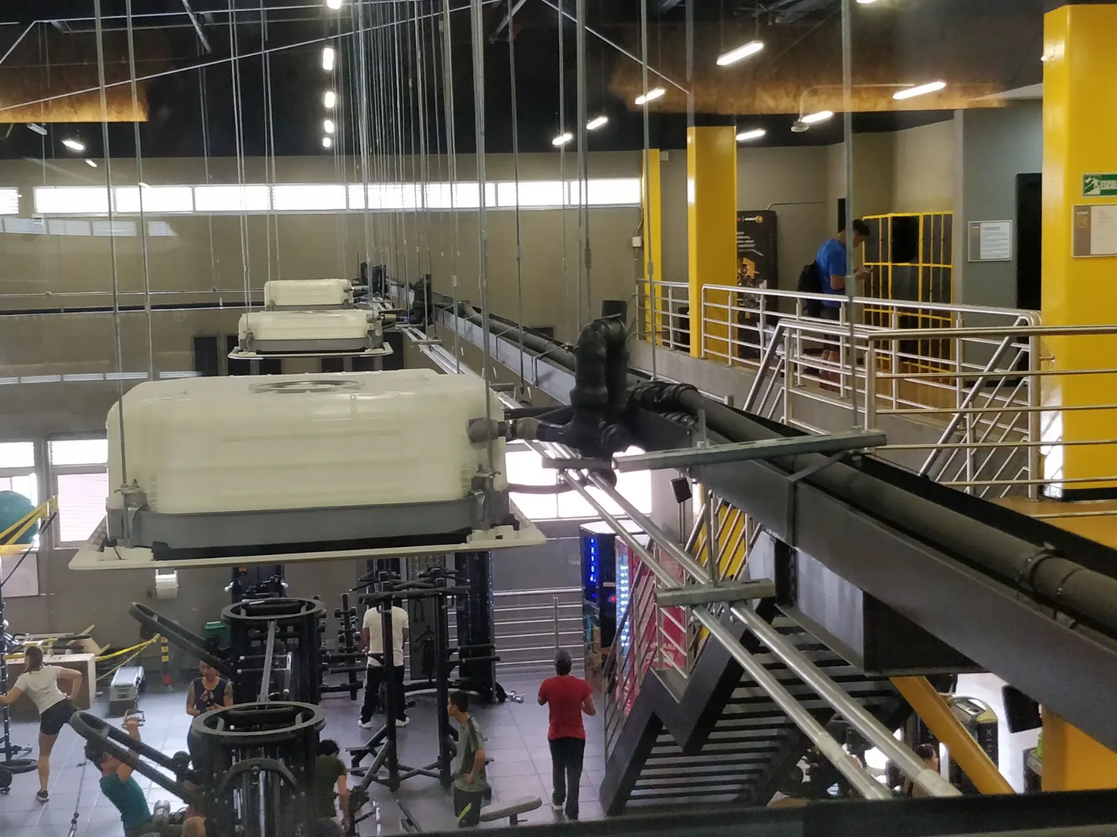 Cassettes colgados durante su montaje sobre la zona de máquinas de un gimnasio