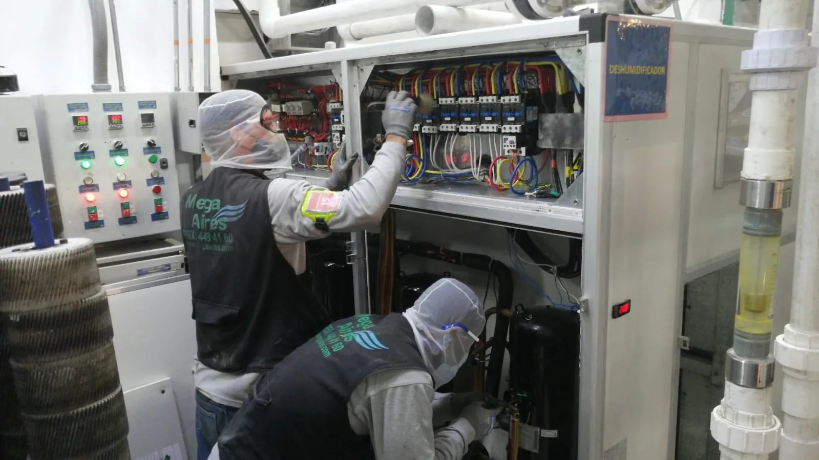 Técnicos de Mega Aires, con su chaleco de la empresa, haciendo mantenimiento a un deshumidificador industrial